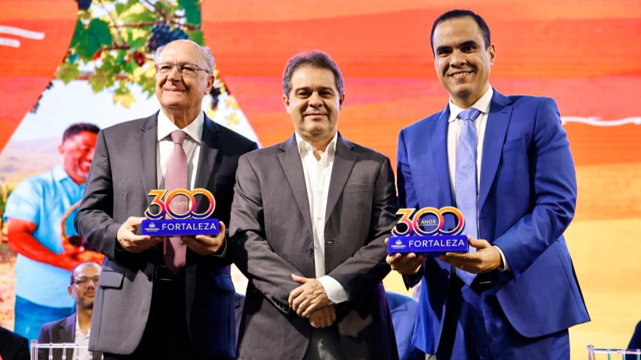 O prefeito Evandro Leitão, o vice-presidente Alckmin e o ministro do Turismo Gustavo Feliciano posam para foto segurando um objeto comemorativo dos 300 anos de Fortaleza